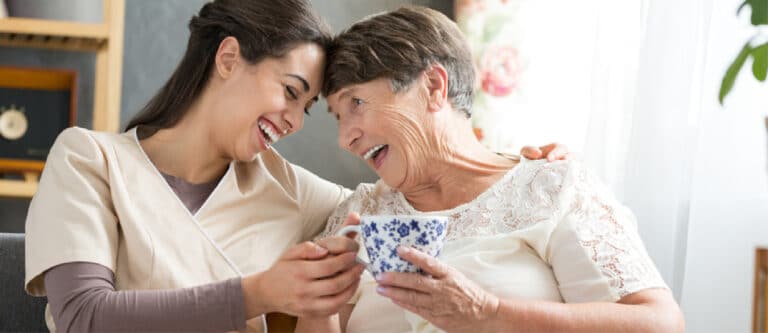 elderly person laughing with caregiver